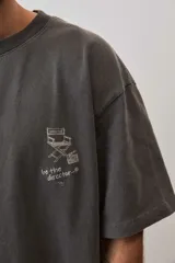 Remera marrón oversize de manga corta, con cuello redondo y pequeño estampado gráfico en el pecho.