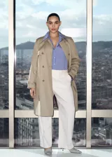Trench coat de corte recto y diseño cruzado, confeccionado en algodón con acabado repelente al agua. Presenta cuello de solapa, cierre frontal con botones efecto carey, cinturón ajustable en la cintura, trabillas en los puños y abertura posterior en el bajo.