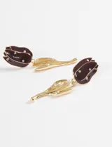 Aros colgantes con diseño de tulipán, compuestos por una flor esmaltada en color bordó con incrustaciones de cristales y un tallo de metal plateado con detalles de hojas y cristales.