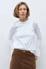 Remera de manga larga color terracota, con cuello alto y detalles de broderie en los hombros y puños acampanados.