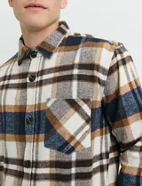 Sobrecamisa de manga larga con diseño a cuadros, cuello camisero y bolsillo frontal. Confeccionada en tejido de poliéster y algodón, sin forro.
