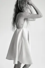 Vestido corto color beige, con escote en V pronunciado, tirantes finos ajustables, corte bajo el busto y falda acampanada con vuelo.