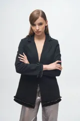 Blazer de denim negro con solapas, puños y ruedo decorados con volados desflecados. Presenta dos bolsillos frontales tipo parche y un corte estructurado.
