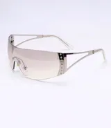 Lentes de sol plateados con forma futurista y apliques de strass en el lateral.