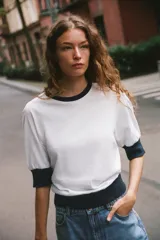 Camiseta de algodón color blanco con cuello redondo, mangas cortas y bajo abullonado, con detalles en color azul marino en el cuello, los puños y el ruedo.