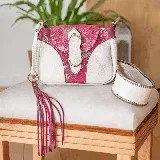 Morral de cuero vacuno blanco con detalles en cuero fucsia y herrajes dorados. Tiene bolsillo trasero con cierre, cierre superior y tapa con broche. Incluye correa larga ajustable y removible. El interior está forrado y tiene un bolsillo para el móvil.