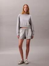 Buzo cropped de cuello redondo, confeccionado en algodón regenerativo, con puños y dobladillo en punto canalé y detalle de insignia con logotipo de la marca.