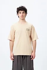 Remera color beige con cuello redondo y mangas cortas. Estampado en el frente con la palabra "UNLEARN" repetida tres veces.