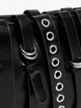 Bandolera negra de cuero con múltiples correas con hebillas y ojales metálicos.