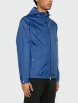 Campera impermeable Moncler modelo Etiache color azul, con capucha ajustable, cierre frontal, bolsillos laterales con botón a presión y parche con el logo de la marca en la manga.