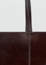 Bolso tipo shopper de diseño estructurado en color bordó con acabado brillante y efecto arrugado. Cuenta con doble asa larga para llevar al hombro y costuras verticales decorativas en el frente.
