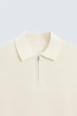 Polo de manga corta, color azul medio, tejido en punto perlado con cuello solapa y cierre frontal de cremallera.