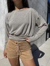 Buzo de tela angorina elastizada color gris, con diseño de cuello bote que permite usarlo con un hombro descubierto. Presenta un corte amplio en la parte superior y una cintura ajustada, con mangas largas.