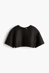 Cropped top negro con leve brillo, de manga corta, escote redondo, hombros caídos y cierre visible en la espalda.