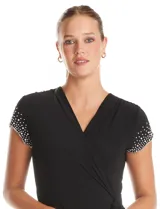Enterito de seda fría color negro, con escote en V cruzado, mangas cortas decoradas con apliques de brillo y perlas, cintura elástica con lazo lateral ajustable y pierna de corte recto.