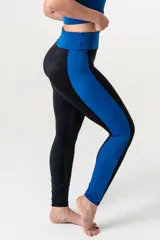 Calza deportiva de tiro alto con cintura elástica reforzada. Presenta un diseño bicolor que combina paneles laterales y faja con estampado animal print en tonos coral y turquesa sobre una base negra.