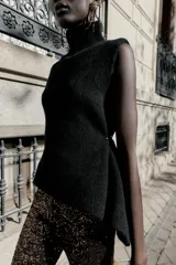 Top de punto color verde militar, con cuello subido y manga sisa. Presenta apliques dorados en los laterales y un bajo asimétrico.