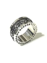 Anillo de acero quirúrgico plateado con diseño giratorio, grabado lateral con tipografía gótica y banda central texturizada con detalles en relieve.