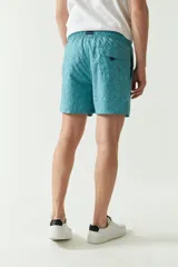 Short de baño con estampado de hojas en tonos azules, cintura elástica con cordón ajustable, bolsillos laterales y bolsillo trasero. Cuenta con logo bordado y tejido ligero de secado rápido.