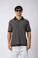 Chomba de tejido de punto con diseño de rayas verticales en blanco y negro, cuello polo clásico y mangas cortas con terminación acanalada.