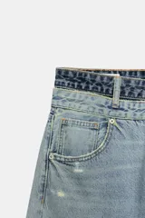 Jeans de tiro medio con cinco bolsillos, diseño holgado y efecto desgastado con detalles de rotos. Cuenta con una cintura doble combinada en contraste de tonos denim y cierre frontal con cremallera y botones metálicos.