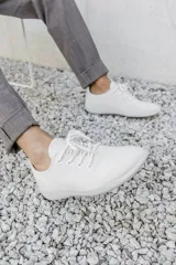 Zapatilla de diseño minimalista confeccionada en lana merino, con cordones al tono y suela de EVA. Presenta un estilo atemporal y versátil, ideal para uso diario.