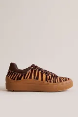 Championes urbanos de cuero con estampa animal print tipo tigre en tonos marrones y beige. Tienen suela de goma marrón y cordones al tono.