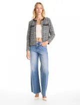 Chaqueta de tweed con cuello a la base, manga larga y abertura central. Presenta bolsillos frontales decorados con apliques de cinta y cadena, y cuenta con forro interno.