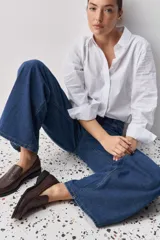 Camisa de algodón blanca, de calce relajado, con cuello clásico, mangas largas y cierre frontal con botones.