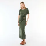 Vestido midi color verde militar, con mangas cortas, cuello redondo y detalle drapeado en la cintura con hebilla metálica dorada circular.
