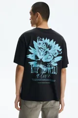 Remera de algodón negra, de corte holgado y diseño de hombros caídos. Presenta un pequeño estampado en el pecho con una flor celeste y el texto "KEEP THE WILD ALIVE".