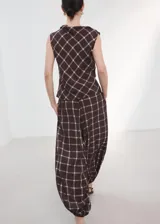 Pantalón balloon de tiro medio en color marrón oscuro con estampa de cuadros. Cuenta con cintura ajustable con goma y cierre de lazo, además de dos bolsillos laterales y diseño abuchonado en los tobillos.