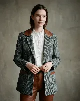 Blazer de paño de lana con diseño de pata de gallo en tonos gris y negro. Presenta cuello y detalles en los bolsillos de cuero color suela, con un corte relajado y cierre frontal de botones.