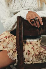 Pack de dos anillos metálicos dorados con detalles en resina negra y diseños florales. Uno de los anillos es ovalado con flores rojas y fucsias, y el otro tiene forma de corazón con un pájaro y flores.