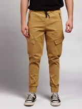 Pantalon cargo de sarga color tostado, con cintura elástica y cordón de ajuste, bolsillos laterales con solapa y puños elásticos en los tobillos.