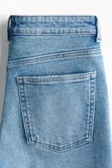 Jean tobillero de cinco bolsillos en denim de algodón con leve stretch, tiro alto y piernas rectas con pliegues frontales y posteriores.