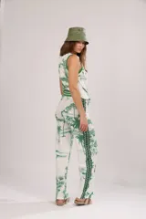 Pantalón de algodón blanco con estampado de palmeras, camellos y aves en color verde.