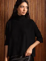 Poleron negro de tejido de punto con cuello alto doble y mangas 3/4 con puños acanalados.