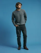Pantalon denim de cinco bolsillos, corte recto y color negro, con botones y remaches metálicos en tono plata viejo.