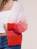 Cárdigan de punto abierto y calado con silueta holgada y hombros caídos, diseño degradado en tonos blanco, rosado y rojo. Presenta frente abierto sin botones y mangas largas abullonadas con terminación en puño acanalado.