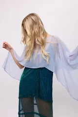Poncho corto de chiffon color amarillo verdoso con textura plisada y brillo metálico. Presenta un cuello redondo y mangas amplias tipo capa.