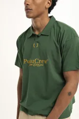 Remera de manga corta color verde oscuro, estilo polo con cuello y abertura frontal. Presenta un bordado central con el texto "PulauCrew" y un laurel en la parte superior.
