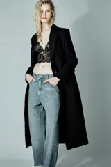 Abrigo largo entallado de Zara, confeccionado en mezcla de lana, con cuello solapa, manga larga, cierre frontal con botones, bolsillos con solapa y abertura en la espalda.