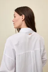 Camisa celeste de corte oversize, con mangas largas, cuello camisero y cierre frontal de botones.