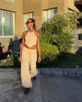 Top de punto color beige, con escote halter y espalda descubierta. Presenta un detalle de caracoles y cuentas en el bajo. Es de talle único y regulable.