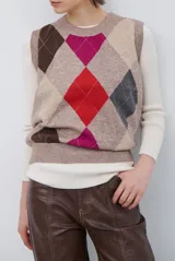 Chaleco de punto con diseño de rombos en tonos beige, marrón y gris. Presenta cuello redondo y corte ajustado a la cintura.