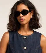 Chaleco de jeans azul oscuro, sin mangas, con cuello redondo y cierre frontal de botones blancos. Presenta un corte ligeramente alargado y solapas frontales que simulan bolsillos.