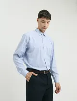 Camisa de manga larga con estampado de rayas verticales en azul y blanco, cuello clásico y bolsillo frontal.