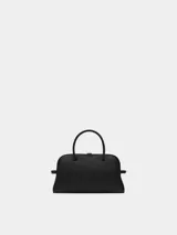 Cartera tipo bowling de cuero granulado negro, con asas superiores, correa ajustable y extraíble, y detalle de lazo en el lateral.