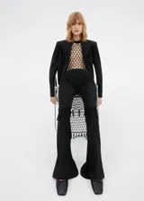 Pantalón negro acampanado de lana, con dos bolsillos de ribete en la parte delantera.